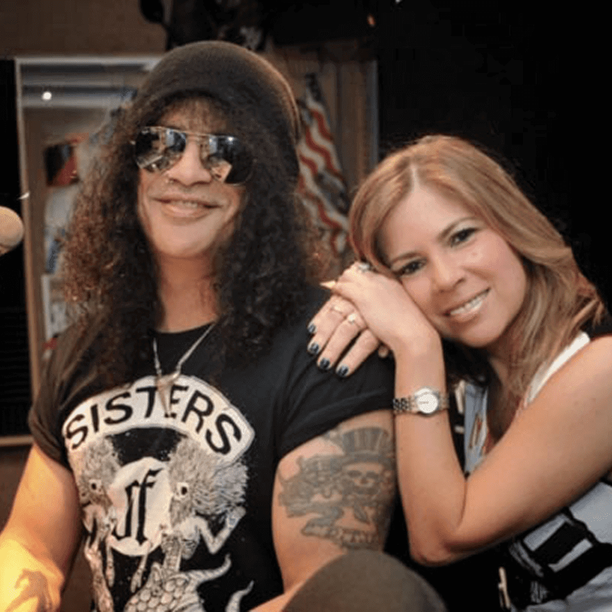 Two women smiling, one wearing sunglasses and a black hat.