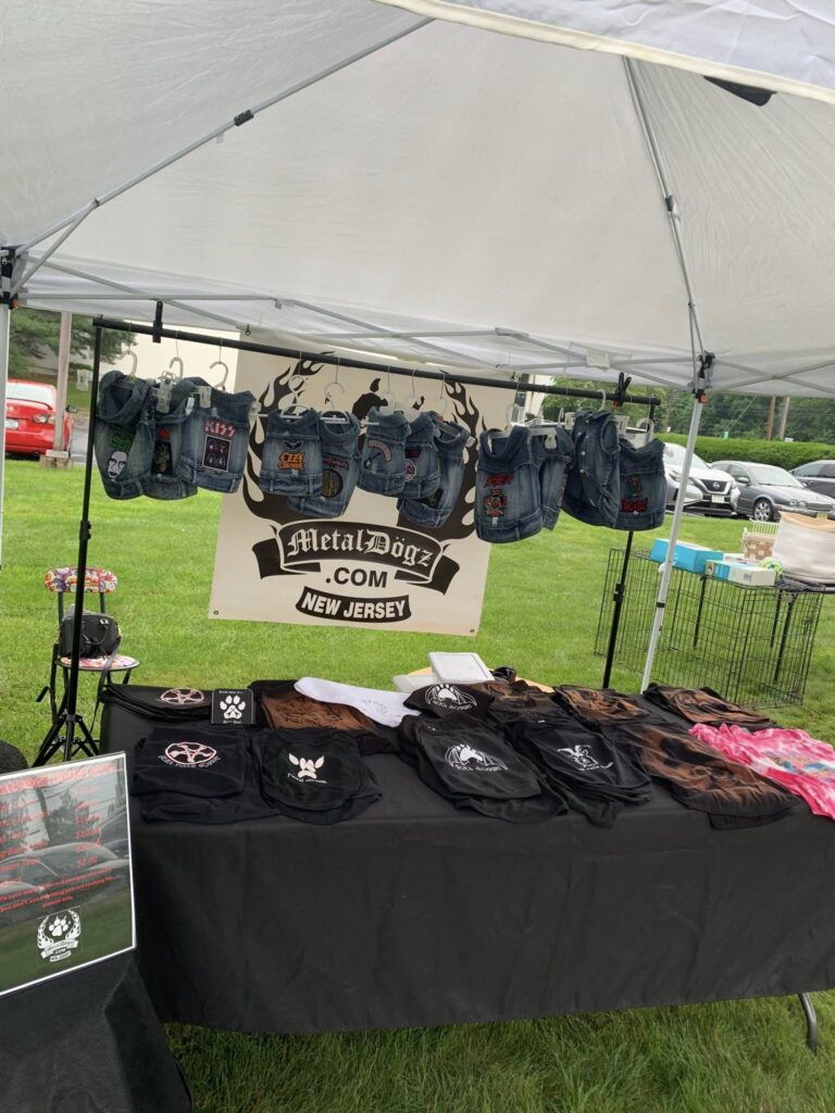 Outdoor stall selling leather goods and accessories under a white tent.