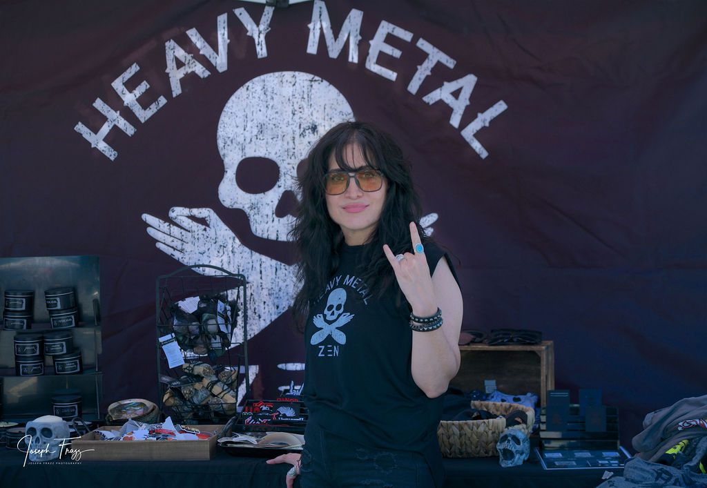 Person in black heavy metal attire making the rock hand sign.