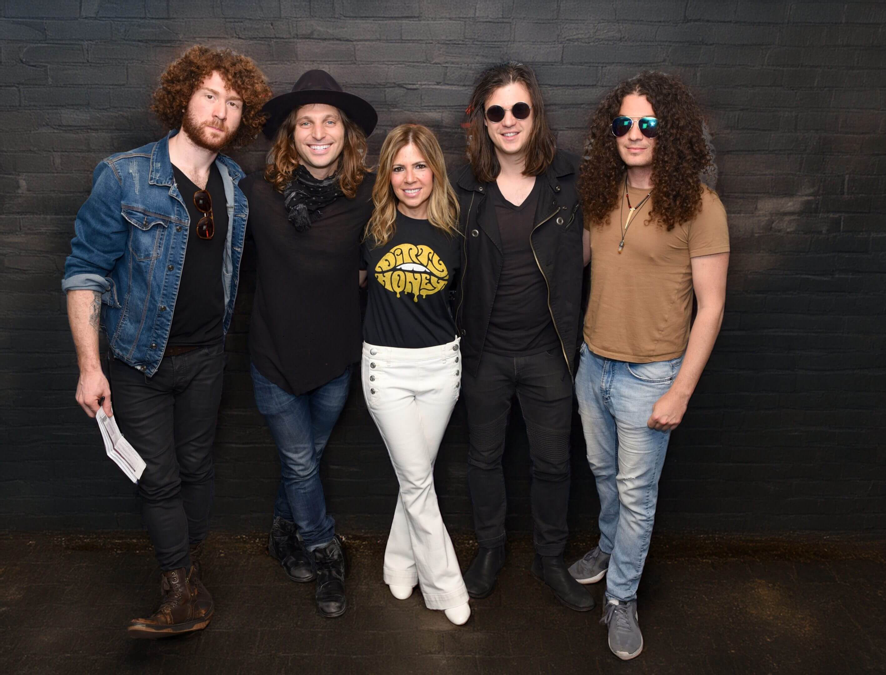 Five casually dressed people posing against a dark wall.