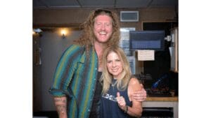 Two people smiling in a recording studio.