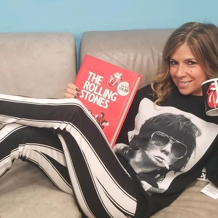 Person lounging on a couch with a red book and a cup.