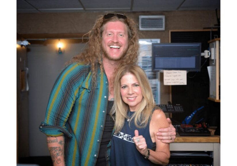 Two people smiling in a recording studio.